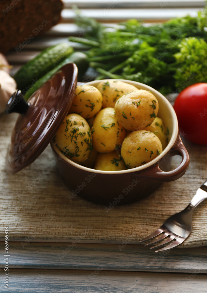 Young boiled potatoes in pan on wooden table