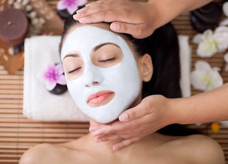 Spa therapy for young woman having facial mask at beauty salon