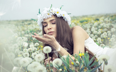 Wall Mural - Beautiful woman blowing dandelions