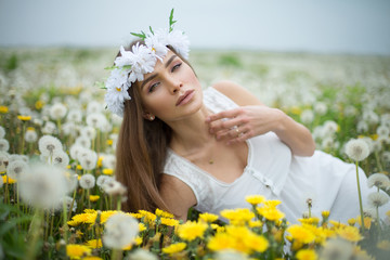 Wall Mural - Alluring woman lying on a meadow full of dandelions