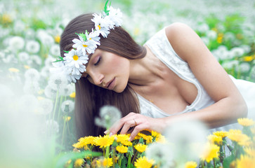 Wall Mural - Young beautiful woman lying on a meadow of dandelions