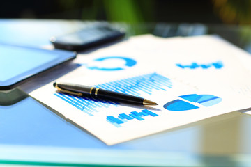 Financial charts on the table with tablet and pen