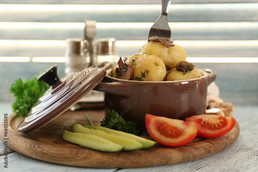 Young boiled potatoes in pan with vegetables on wooden table