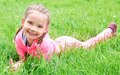 portrait of adorable smiling little girl lying on grass