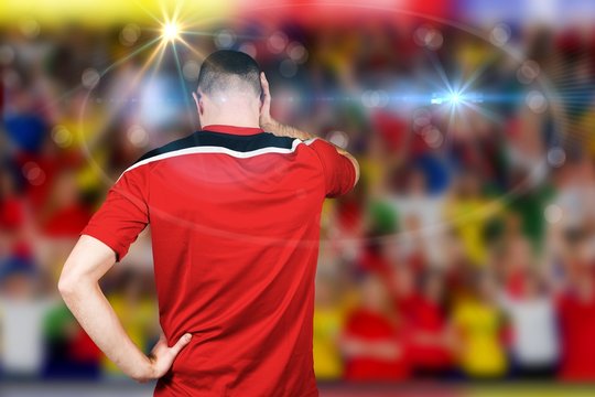 Composite image of disappointed football player looking down