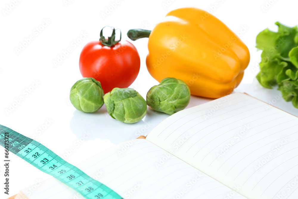 Book with measuring tape and vegetables isolated on white