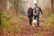 © Monkey Business - Couple Walking Dog Through Winter Woodland