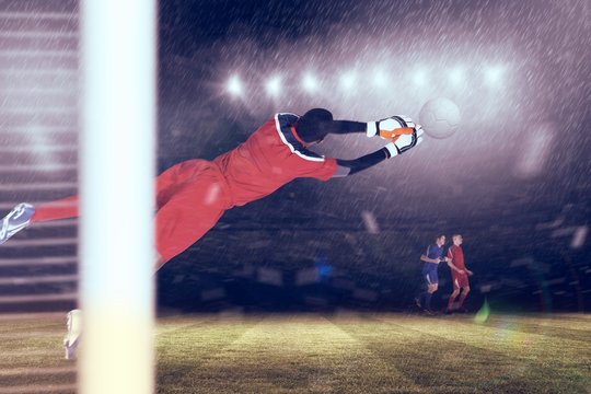 Composite image of goalkeeper in red making a save
