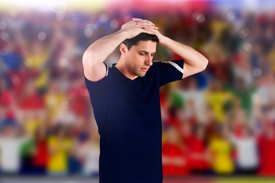 Composite image of disappointed football player looking down