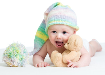 funny baby boy lying on bed with plush toy