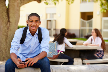 Male High School Student Using Phone On School Campus