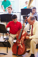 Wall Mural - boy learning to play cello in high school orchestra