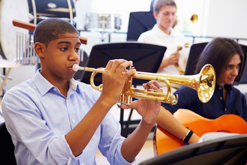 Wall Mural - male pupil playing trumpet in high school orchestra