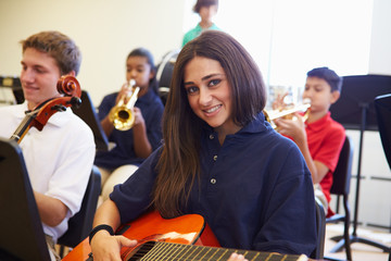 Wall Mural - female pupil playing guitar in high school orchestra