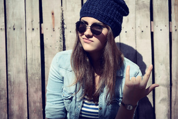 portrait of beautiful cool girl gesturing in hat and sunglasses,