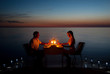 canvas print picture - A young couple share a romantic dinner with candles on the beach