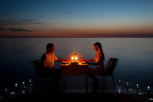 A Young Couple Share A Romantic Dinner With Candles On The Beach