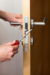 Wall Mural - Hands repairing a door lock