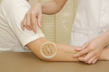 Physiotherapist measuring range of motion patients' elbow with g