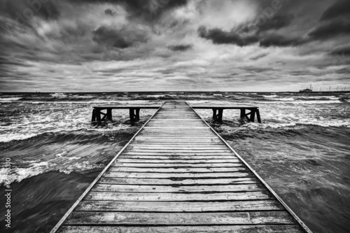 Fototapeta na wymiar Old wooden jetty during storm on the sea. Dramatic sky