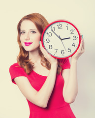 Wall Mural - Surprised redhead girl with huge alarm clock on light background