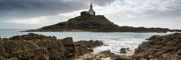 Wall Mural - landscape panorama of mumbles lighthouse in wales with sunbeams