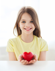 Poster - smiling little girl with red heart at home