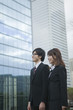 © milatas - ビルの前で立つビジネスウーマンとビジネスマン