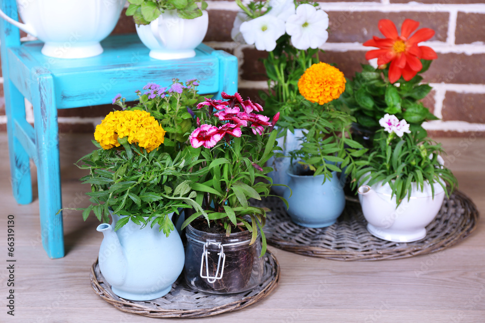 Flowers in  decorative pots on chair, on bricks background