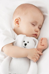 Wall Mural - Carefree sleep little baby with a soft toy on the bed