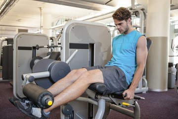 Focused man using weights machine for legs