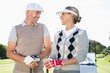 © WavebreakmediaMicro - Happy golfing couple facing each other with golf buggy behind
