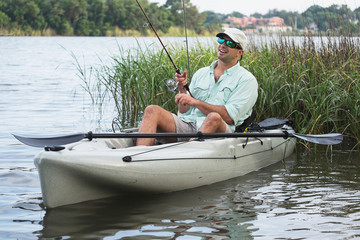 Man Fishing in Kayak in grassy waters