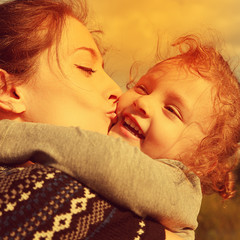 bright closeup portrait of happy mother kissing daughter