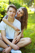 © guas - Portrait happy couple teenagers sitting on the grass in summer