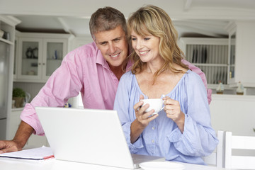 Wall Mural - Mid age couple working at home on laptop