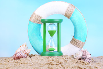 Hourglass in sand on blue sky background