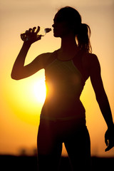 Wall Mural - silhouette of a young sportive woman drinking water