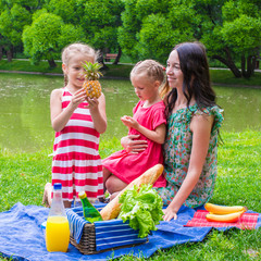 Cute little girl and happy mom picnicking in the park