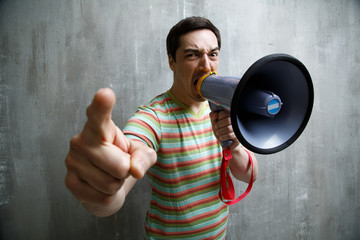 man yells into a megaphone and points on a gray textured backgro