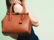 Elegant outfit. Brown leather bag in female hand
