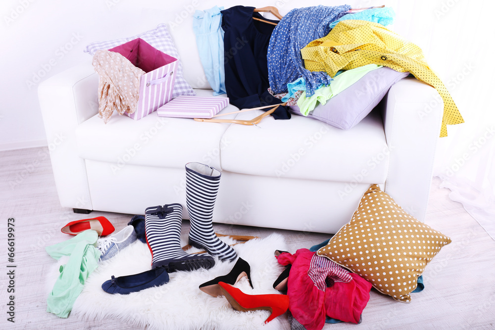 Messy colorful clothing on  sofa on light background