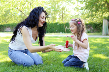 Wall Mural - Happy mom and daughter. Walk in the green park