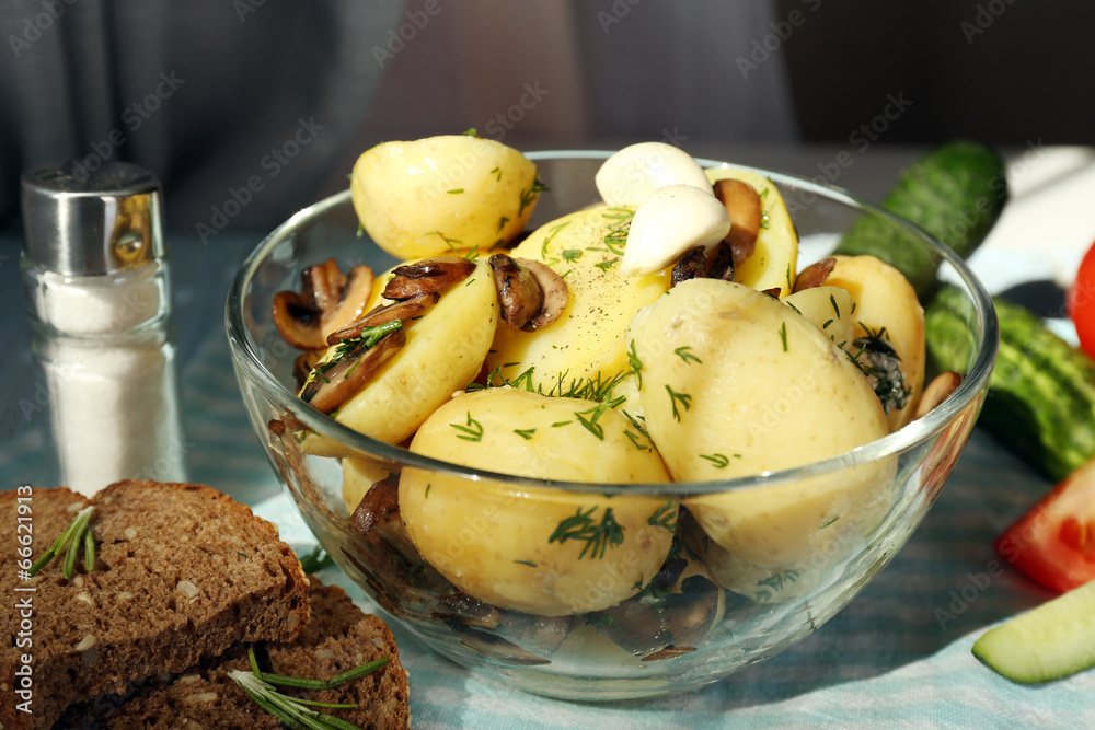 Young boiled potatoes in bowl on wooden table, close up