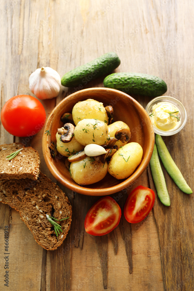 Young boiled potatoes in bowl on wooden table, close up