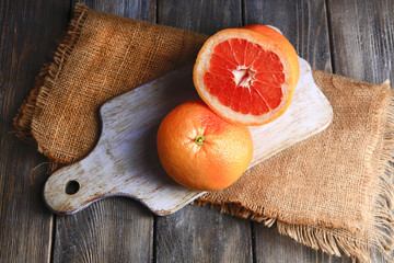 Wall Mural - Ripe grapefruits on cutting board, on wooden background