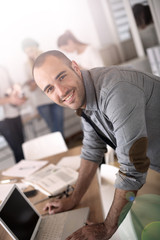 Aufkleber - Smiling young man in office working on laptop