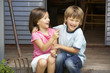 Young brother and sister sitting on veranda