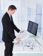 Poster - Businessman Looking At Blueprint At Computer Desk