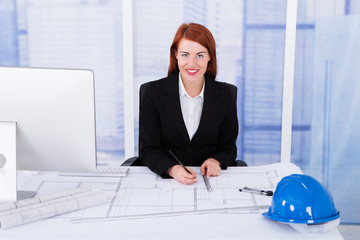 Poster - Businesswoman Using Computer With Blueprints At Desk
